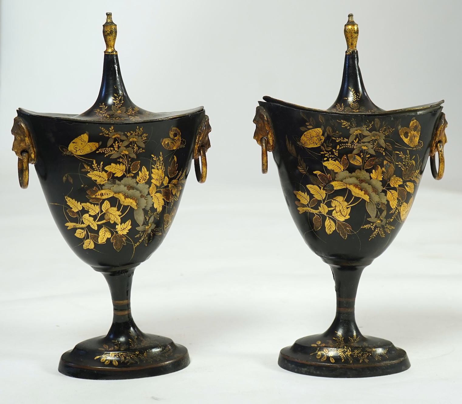 A pair of early 19th century Dutch japanned pewter chest urns and covers, and a tole ware cheese coaster